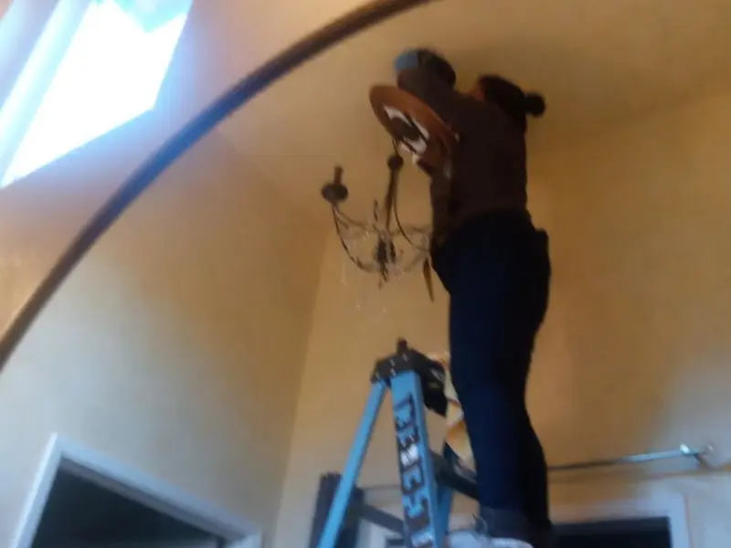 Electrician installing a chandelier in a Charleston residence